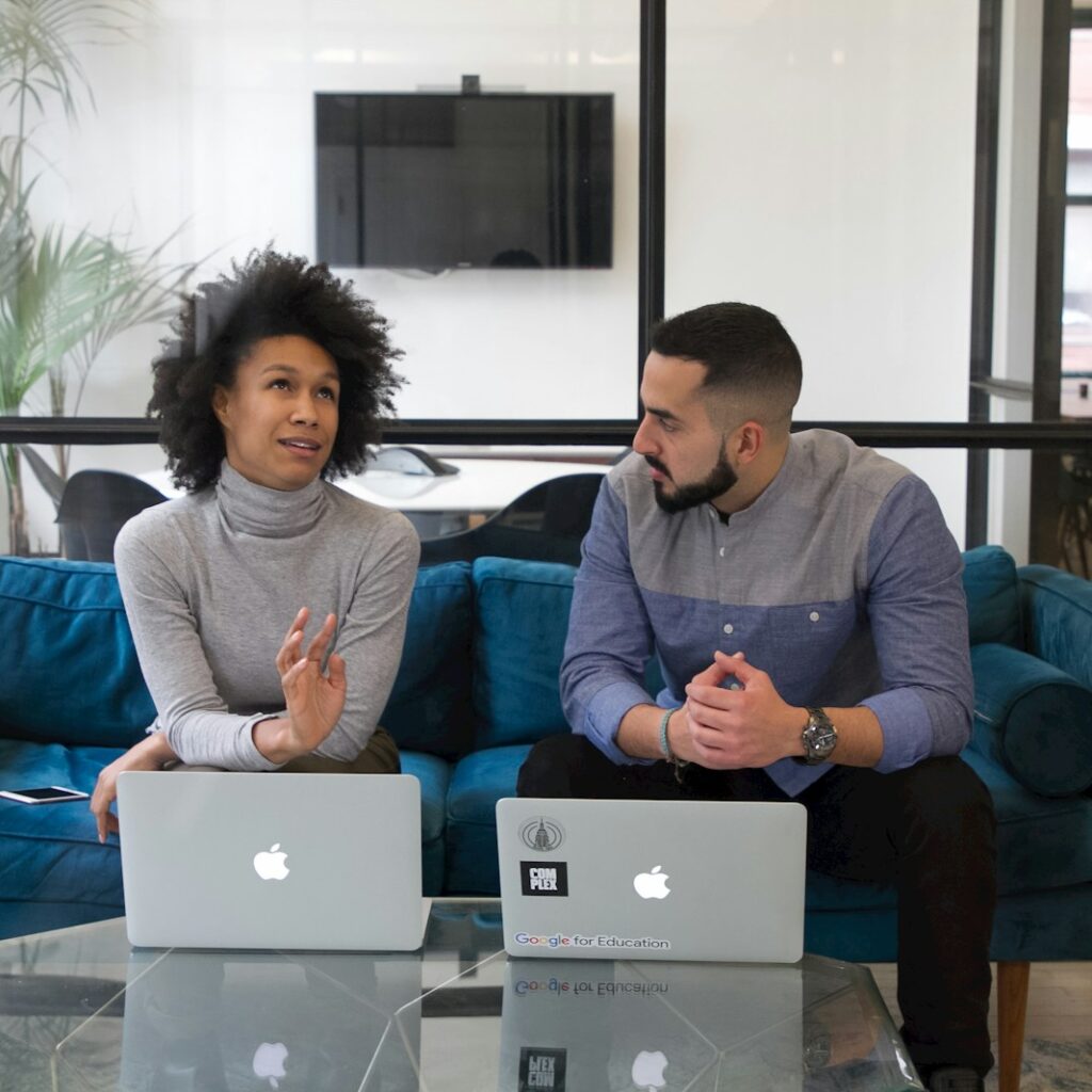 a man and a woman sitting on a couch with their laptops