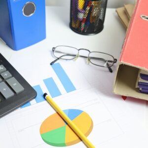 Mesa de escritório com calculadora, gráficos e pastas para revisão financeira