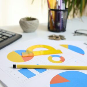 Mesa de escritório com calculadora, gráficos e papéis para revisão financeira
