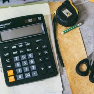Mesa de trabalho com calculadora, documentos e materiais de escritório para conferência financeira e fiscal