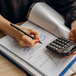 Profissional analisando documento fiscal com calculadora em mesa de trabalho