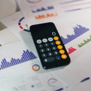 Smartphone com calculadora sobre relatórios financeiros para fechamento fiscal mensal