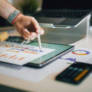Pessoa usando tablet para analisar gráficos e informações financeiras em ambiente de trabalho