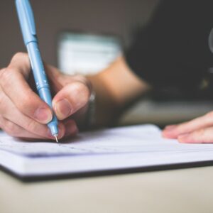 Pessoa revisando anotações e documentos fiscais com uma caneta