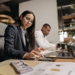Profissional usando calculadora e analisando documentos financeiros em escritório