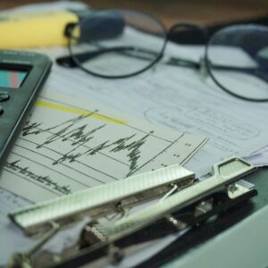 Mesa de trabalho com calculadora, papéis e óculos, sugerindo conferência de caixa e organização financeira