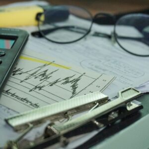 Mesa de trabalho com calculadora, papéis e óculos para rotina financeira