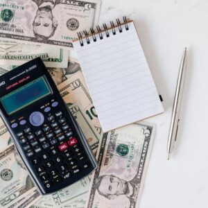 Pessoa organizando documentos financeiros e calculadora sobre a mesa