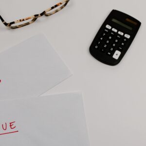 Top view of financial papers labeled 'Paid' and 'Due' beside a calculator and glasses, em uma rotina de revisão fiscal e financeira
