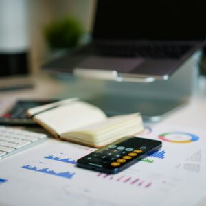 Mesa de escritório com smartphone, documentos e gráficos financeiros para conferência da apuração mensal