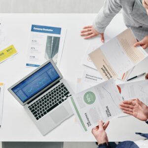 Pessoa conferindo documentos e informações financeiras em uma mesa de trabalho