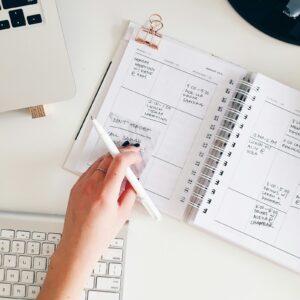 Pessoa segurando bloco de notas e caneta em fotografia de cima, representando checklist de fechamento de outubro de 2026.